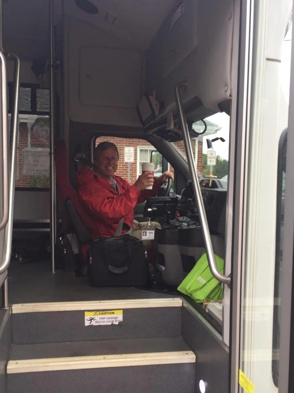 Kevin smiling from the driver's seat of a senior transportation bus