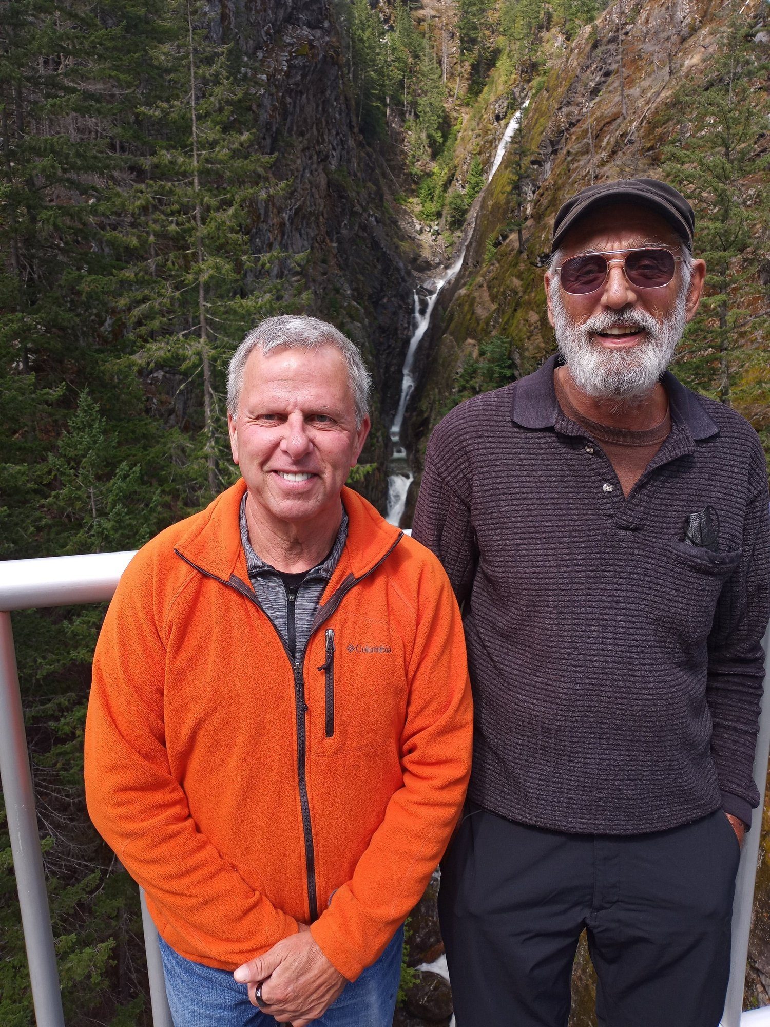 Kevin and an older friend in front of a mountain waterfall